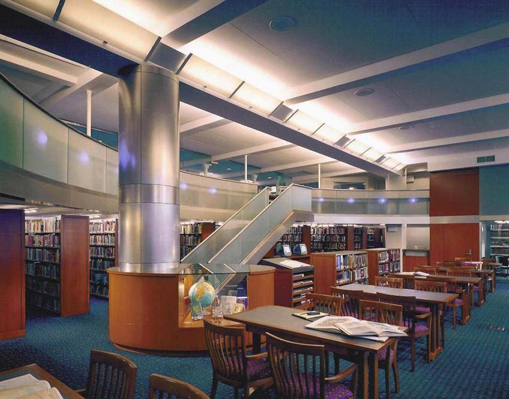 Modern library with two levels, metal columns, and spacious study areas.